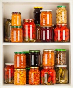 Photo of jars of canned food stacked in a cupboard.
