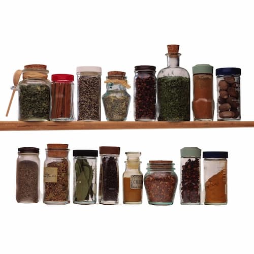 Two rows of spices and herbs in various shape and size glass bottles